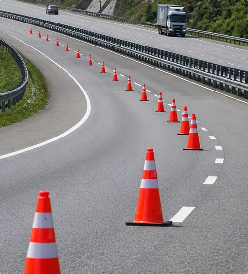 Traffic control cones lining a roadway with vehicles passing safely.