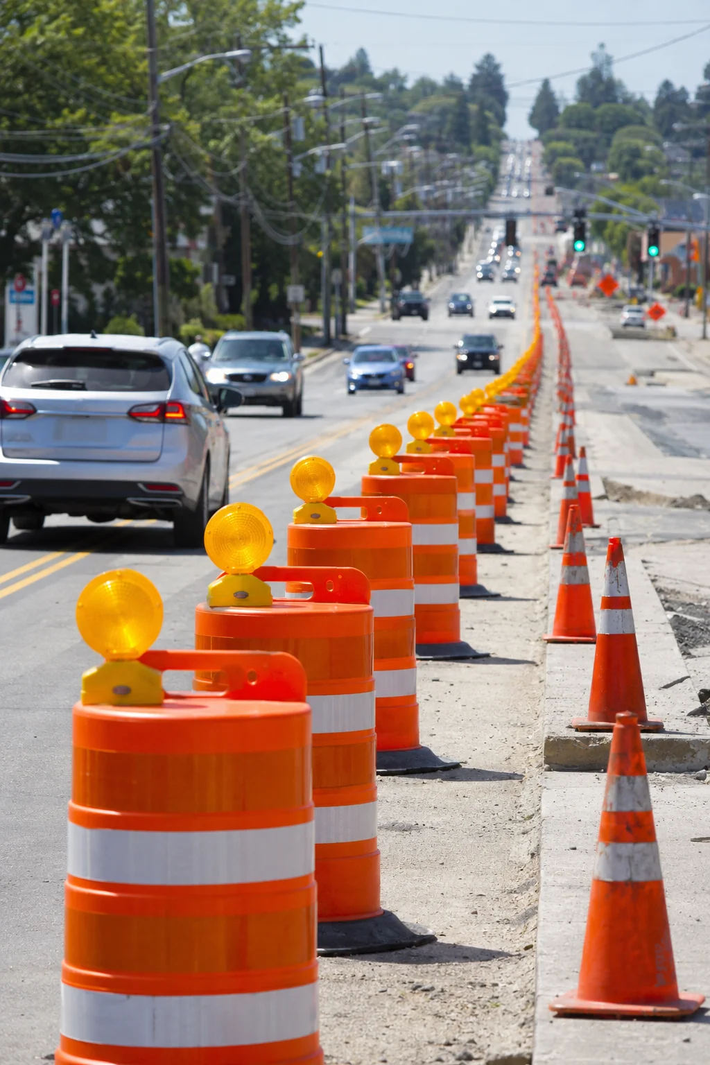 Traffic control cones lining a roadway with vehicles passing safely.